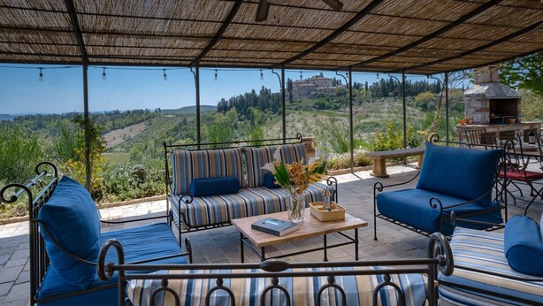 An outdoor seating area with striped sofas and a stone fireplace, overlooking a scenic hillside. - Casa Perano, Gaiole in Chianti, Siena and Chianti (Gaiole in Chianti)