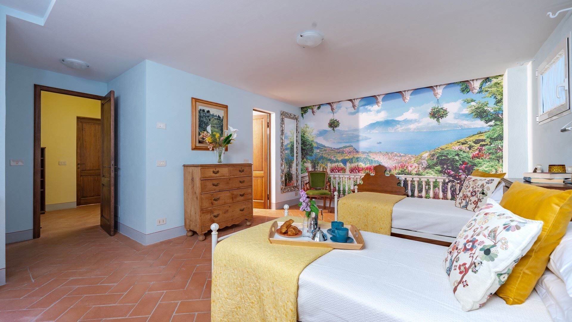 Een slaapkamer met een bed, een dressoir, een stoel en een groot raam met uitzicht.