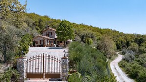 A stone house with a gated entrance, surrounded by lush greenery and a winding road. - Casa Perano, Gaiole in Chianti, Siena and Chianti (Gaiole in Chianti)