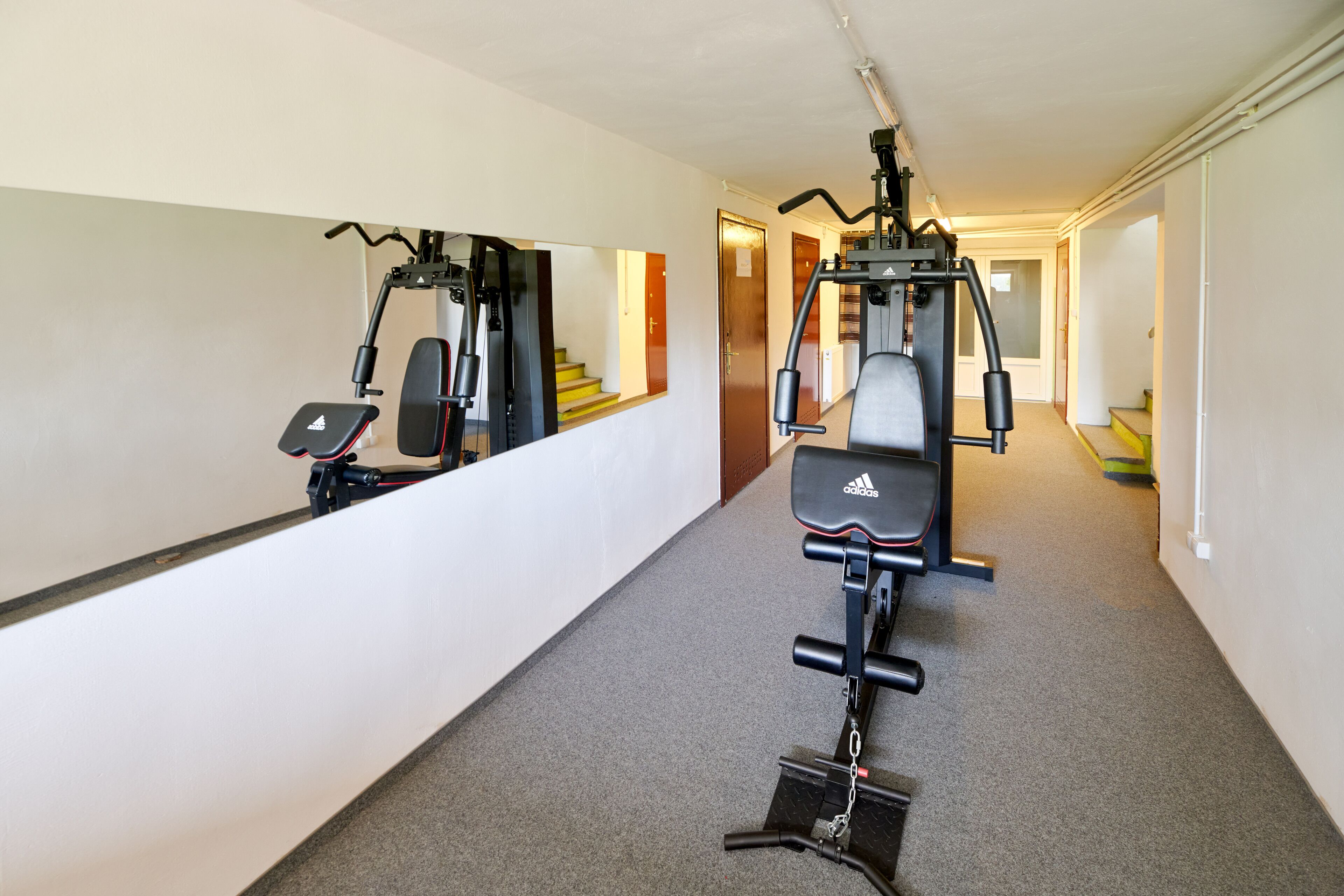 A hallway with exercise equipment, a mirror, and a staircase.