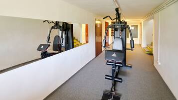 A hallway with exercise equipment, a mirror, and a staircase.