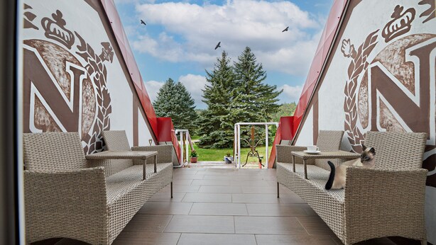 A view of a room with wicker furniture, a large window, and a view of trees and sky. - Park Inn Resort (Miroslawiec)