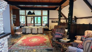 A cozy interior with a stone floor, a red patterned rug, and a dining area with tables set for a meal. - Park Inn Resort (Miroslawiec)