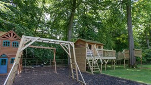 A playground with wooden climbing structures and a swing set. - Luxury country retreat with extensive leisure facilities (Lane End)