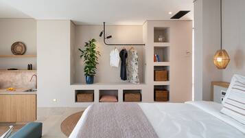 Un dormitorio moderno con una cama grande, una mesita de noche, una lámpara colgante y estanterías empotradas con cestas y una planta en maceta.