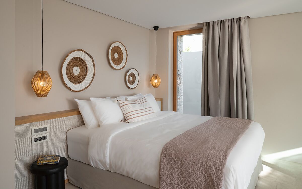Une chambre d’hôtel avec un grand lit, une table de chevet, un radiateur fixé au mur et une fenêtre avec des rideaux.