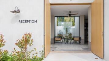 A reception area with a modern design, including a sign labeled "RECEPTION," a ceiling fan, and a glass door leading inside.