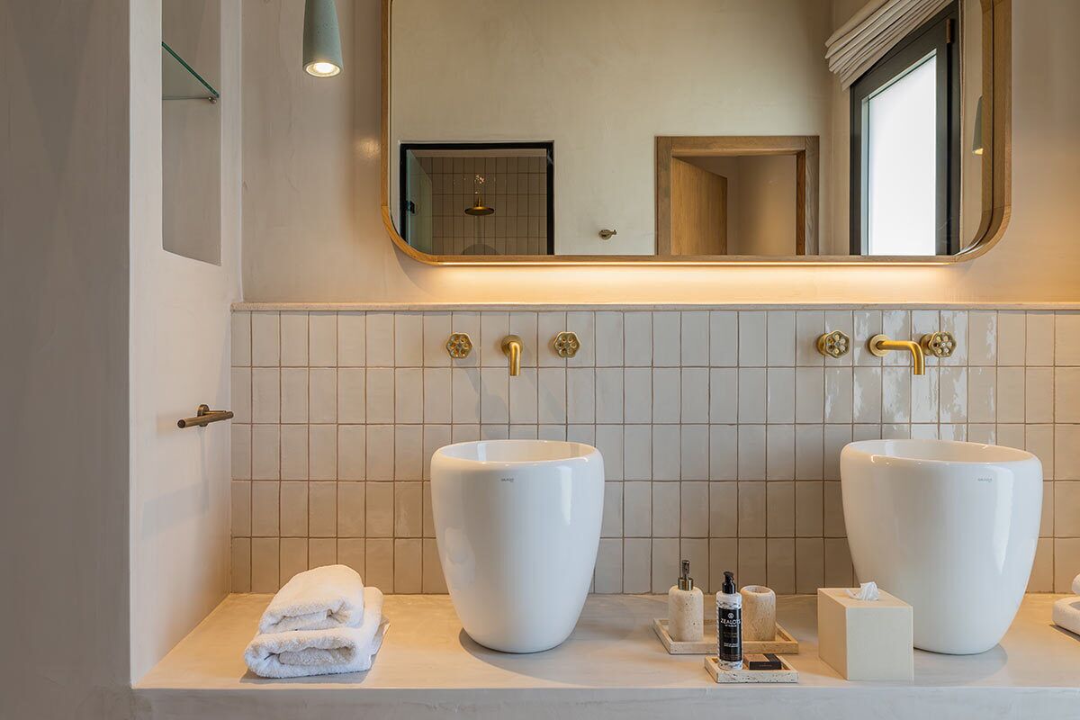 A modern bathroom with two large white sinks, a mirror, and a towel rack.