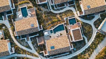 An aerial view of a resort with multiple buildings, each featuring a swimming pool and outdoor seating areas.