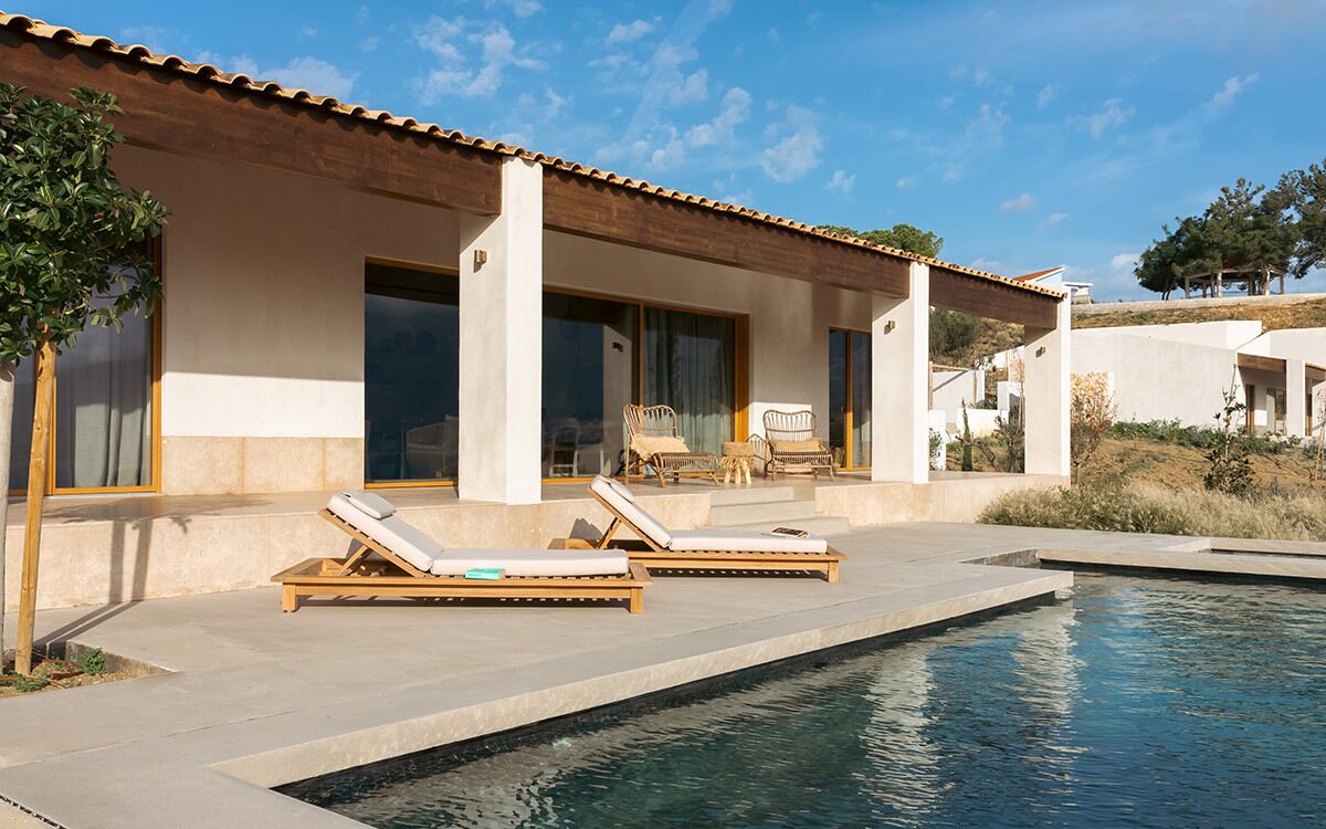 A modern villa with a swimming pool, lounge chairs, and a patio area.
