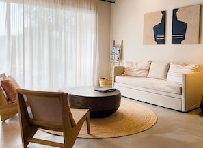 Relax in this stylish living room with a round coffee table, sofa, and wooden chair.