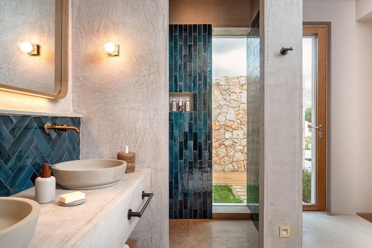 Un baño moderno con dos lavamanos, un espejo y una pared de piedra.