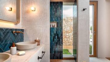 Un baño moderno con dos lavamanos, un espejo y una pared de piedra.