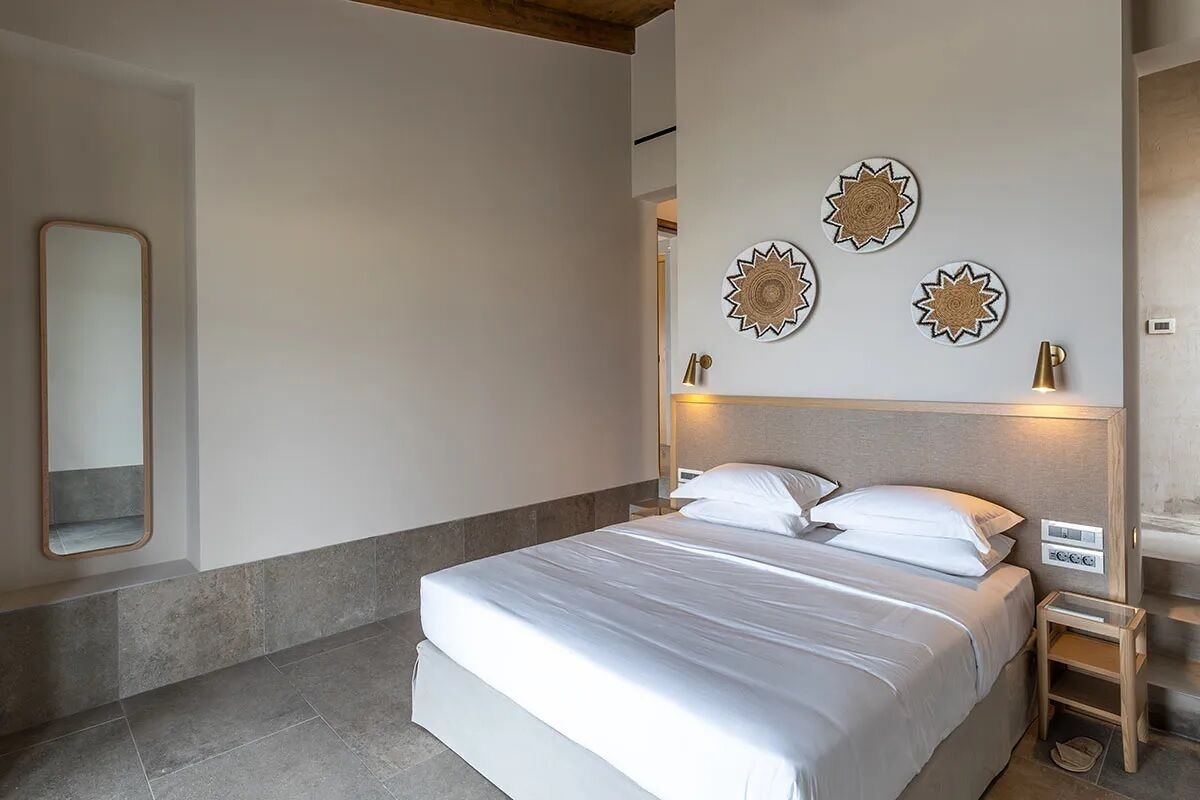 Une chambre à coucher comprenant un lit, une table de chevet, un miroir et des éléments décoratifs sur les murs.