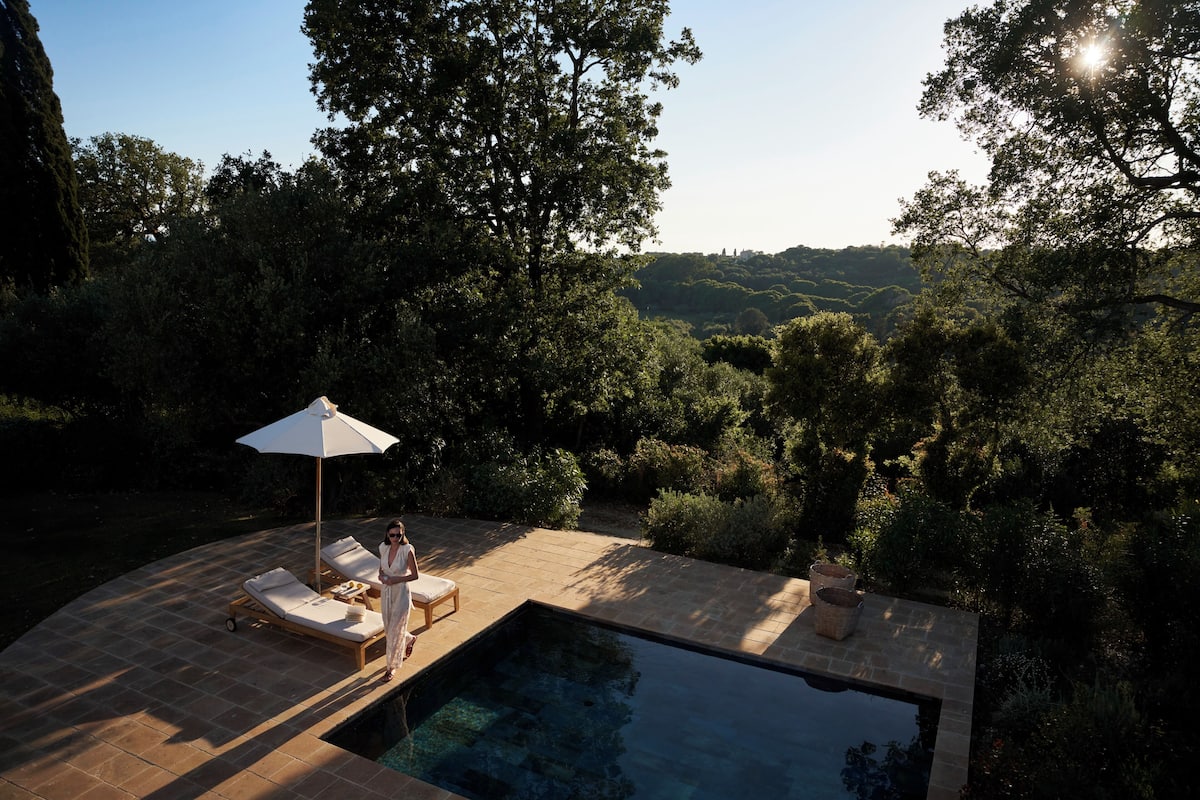 Un área de piscina privada con sillas de descanso y una persona junto a la piscina.