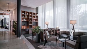 A modern lobby with a reception desk, seating area, and a large bookshelf. - Radisson RED Hotel, Oslo Airport (Ullensaker)