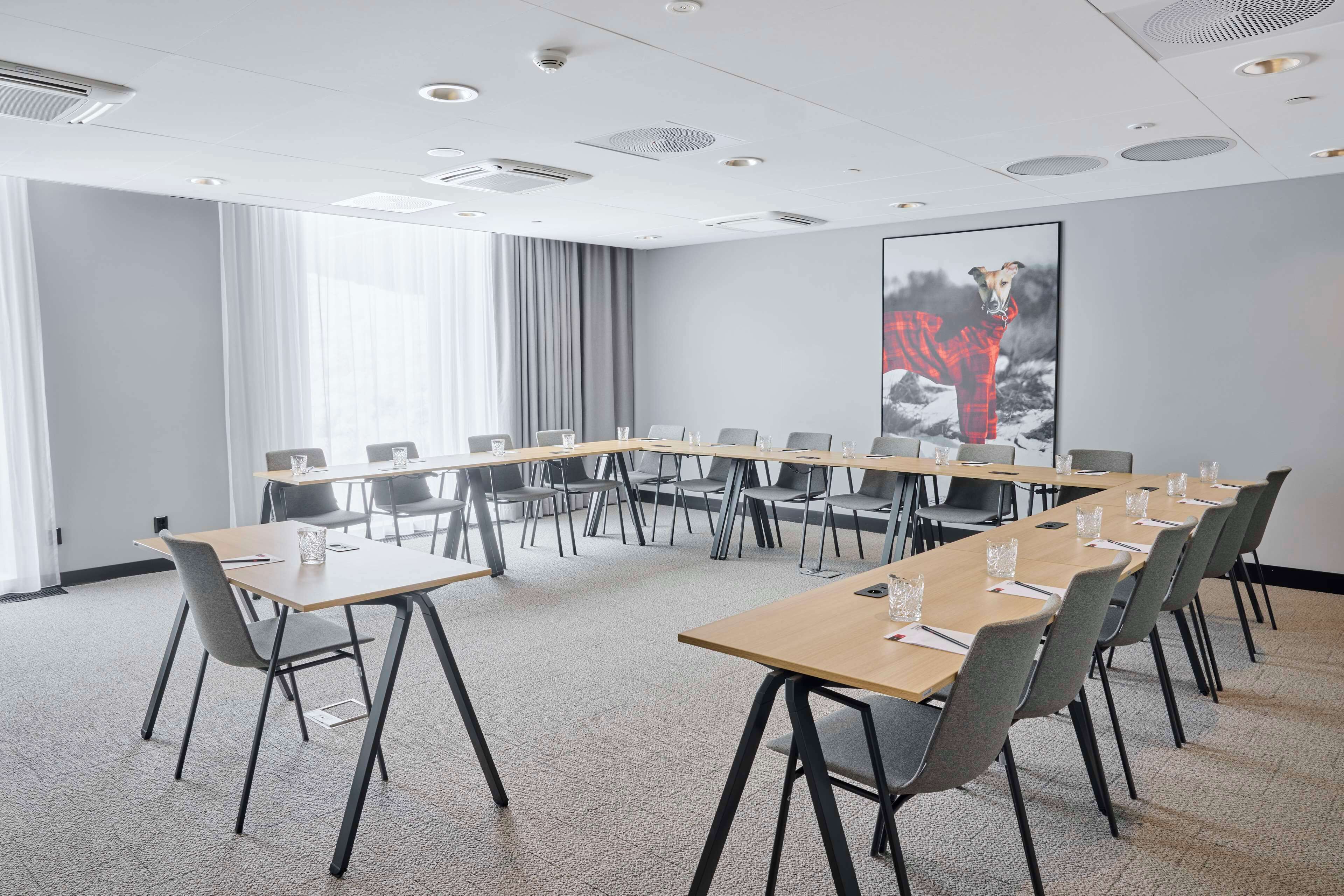 Un salón de conferencias con una mesa larga, sillas y un cartel grande en la pared.