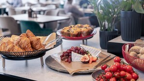 A buffet with croissants, grapes, cheese, and tomatoes.