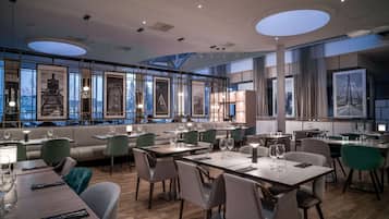 Un restaurante moderno con techos altos, ventanas amplias y mobiliario contemporáneo.