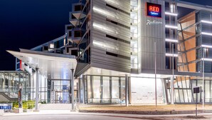 A modern hotel with a prominent 'RED Radisson' sign, multiple floors, and a glass facade.