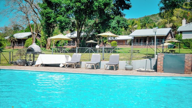 Un área de piscina con sillones de descanso y una parrilla.