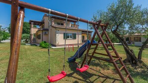 A wooden swing set with two swings and a slide in a grassy yard with a house in the background. - Villa with pool, 6 persons, large garden with barbecue. Dogs are welcome! (Sv. Lovrec)