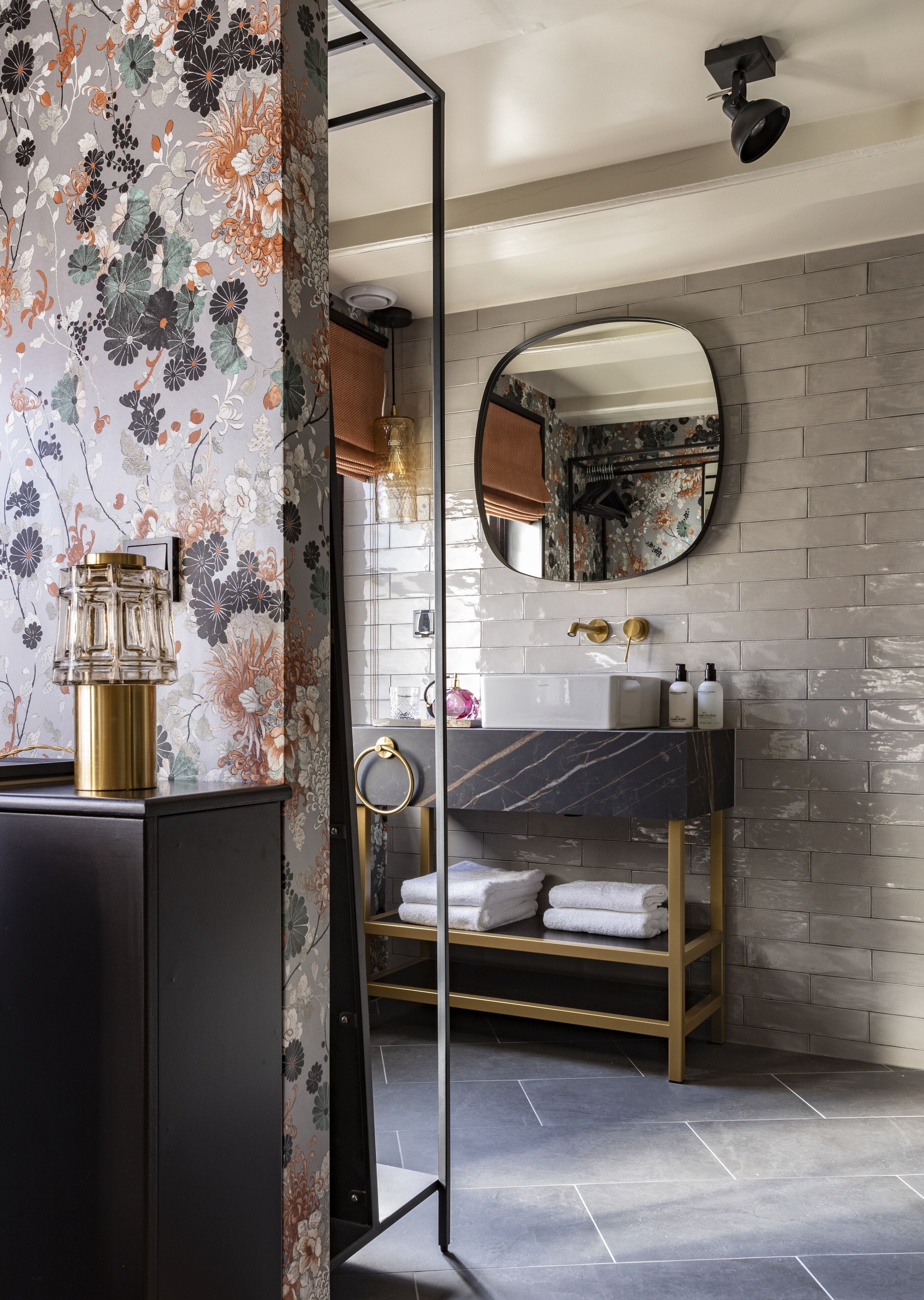 Un bagno moderno con un lavabo in marmo, uno specchio rotondo e un mobile bagno in legno.