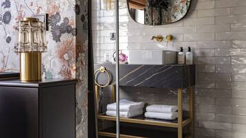 Un bagno moderno con un lavabo in marmo, uno specchio rotondo e un mobile bagno in legno.