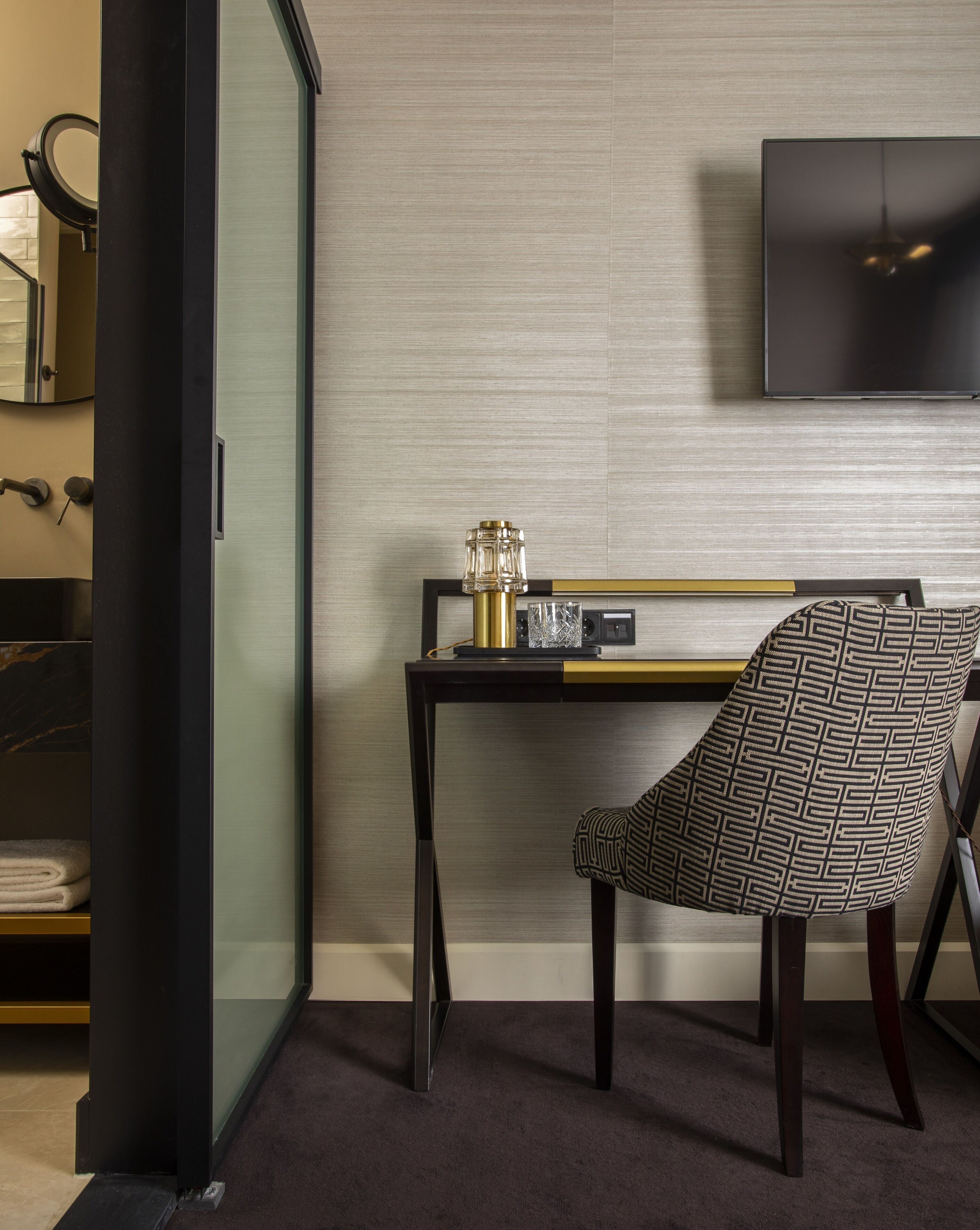Een moderne kamer met een bureau, stoel en een aan de muur bevestigde televisie.