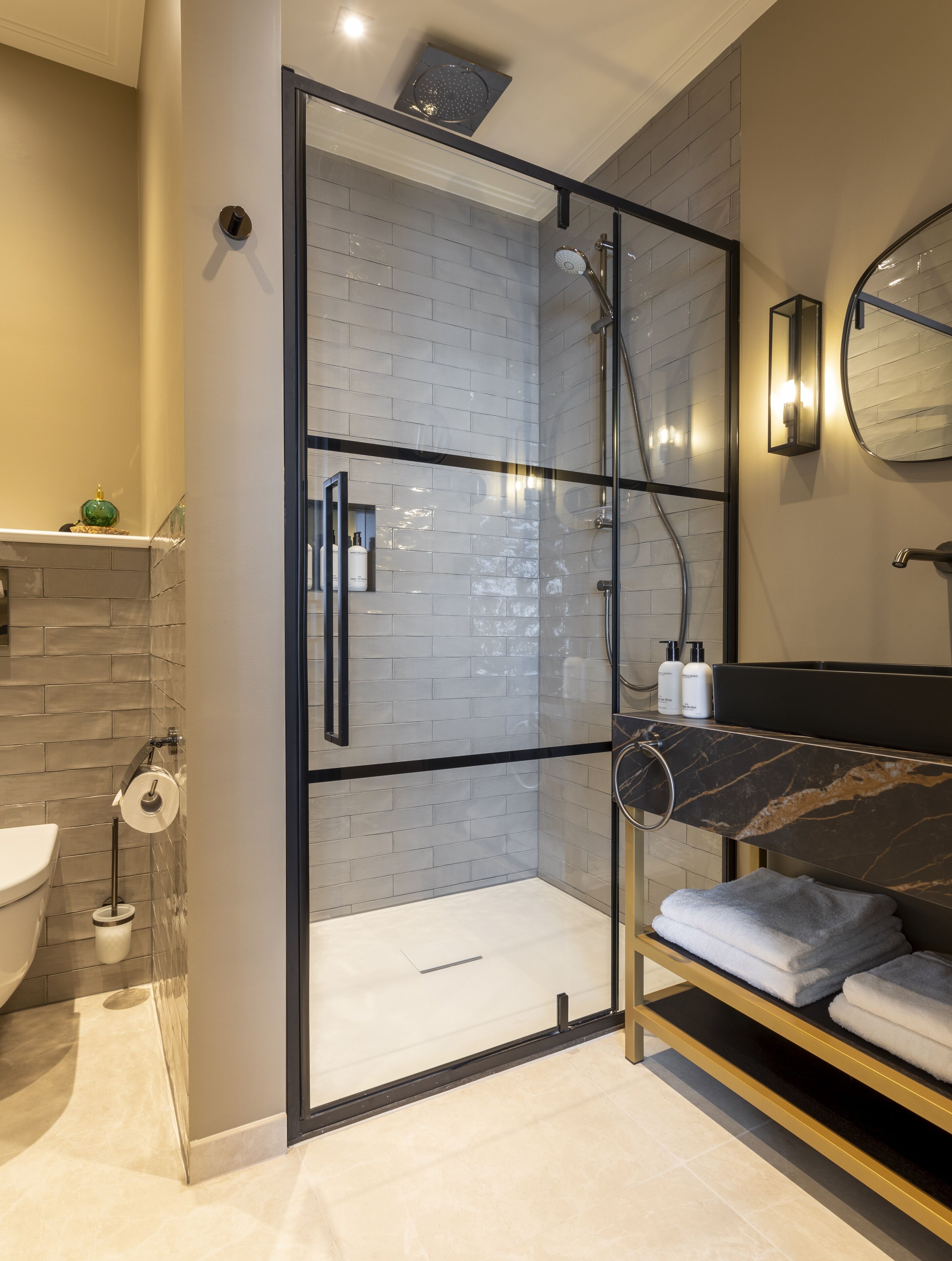 Un baño moderno con ducha de vidrio, lavamanos de mármol y espejo integrado.