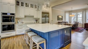 Una cocina moderna con armarios blancos, una isla azul y electrodomésticos de acero inoxidable.