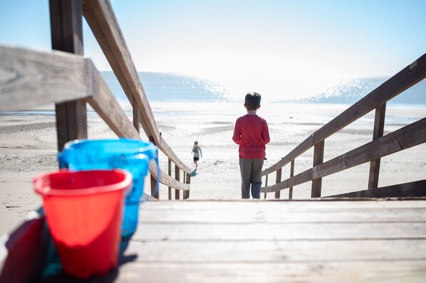 A wooden pier leading to a beach with a child in a red jacket. - Beachfront, Huge Deck and Private Heated Pool (Bolivar Peninsula)