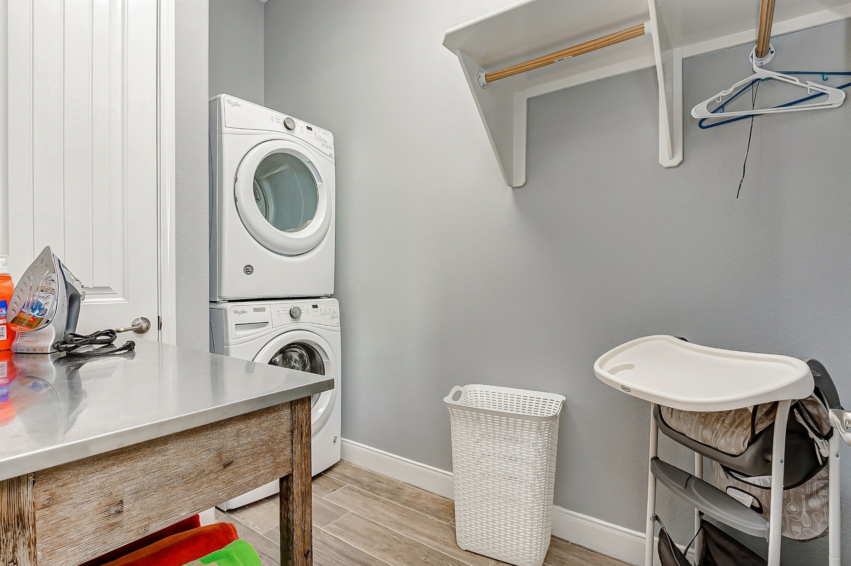 Un espace buanderie comprenant un lave-linge, un sèche-linge et une petite table avec des produits de nettoyage.