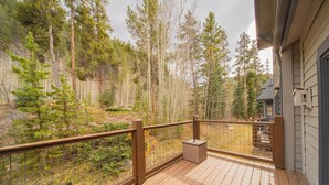 A wooden deck with a metal railing overlooking a forested area. - Forested Townhome w/ Garage, Hot Tub & Shuttle (Keystone)