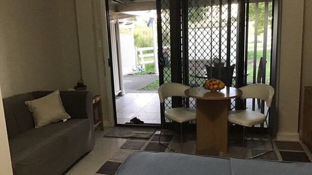 A room with a sofa, a small table with fruit, and a chair.