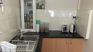A kitchen with a sink, a dishwasher, a toaster, and a cabinet.