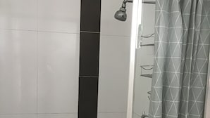 A shower with a glass door, a black vertical stripe, and a geometric-patterned curtain.
