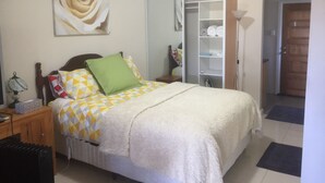 A bedroom with a bed, a nightstand, a lamp, a wardrobe, and a door.