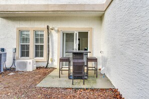 A patio with a table and chairs, air conditioning units, and a door leading to a covered area. - Renovated PCB Studio, 2 Min Walk To Laguna Beach! (Panama City Beach)