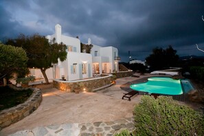 A white villa with a swimming pool and outdoor seating area.