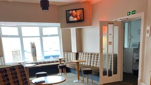 A seating area with sofas, a round table, and a television mounted on the wall. - The Avari Hotel (Blackpool)