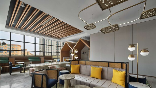 Un espace de détente moderne avec un canapé, des fauteuils et des tables rondes.