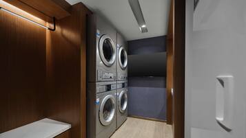 A laundry room with stacked washers and dryers, wooden paneling, and a bench.