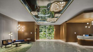 Un hall d’hôtel moderne doté d’un comptoir d’accueil, d’un espace salon et d’un design de plafond original.