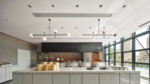 Une cuisine moderne dotée d’un grand îlot central, d  ’appareils électroménagers en acier inoxydable et offrant une vue sur la ville grâce à de grandes fenêtres.