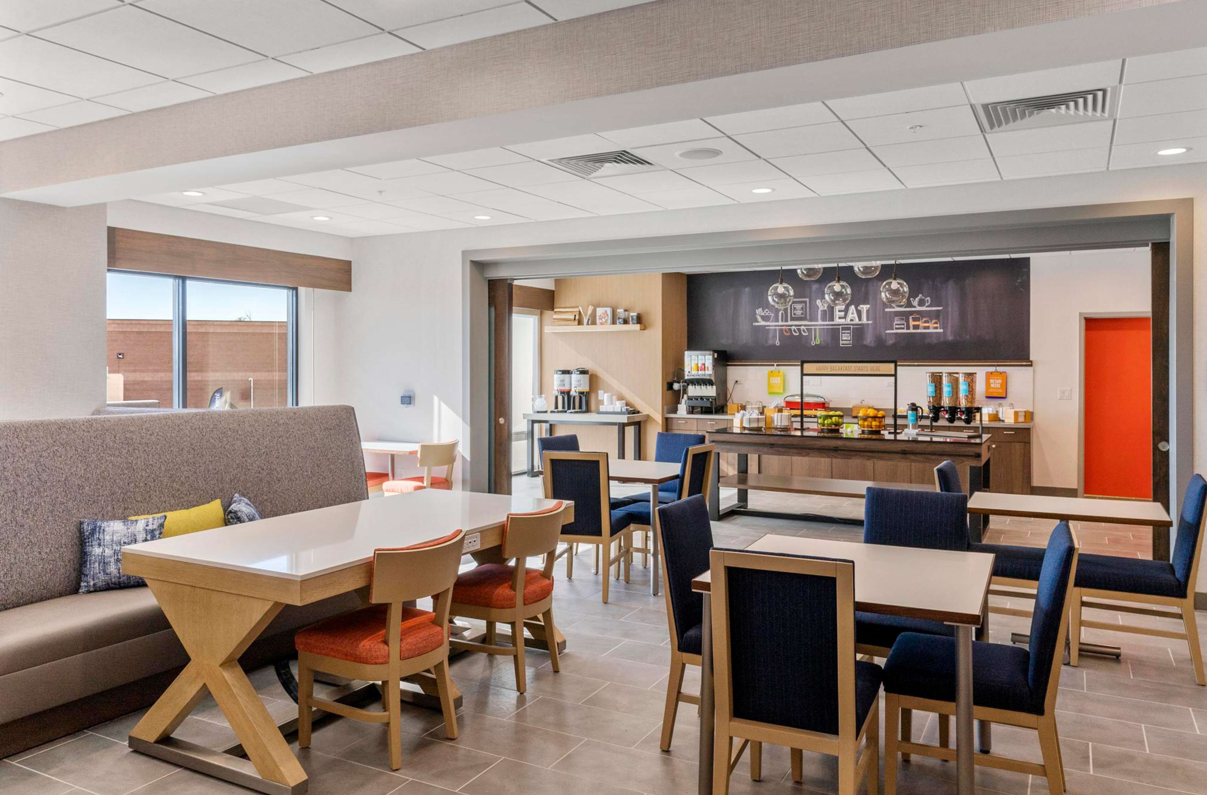 Un café moderne doté d’un bar, de différents espaces pour s’asseoir et d’une cuisine ouverte.