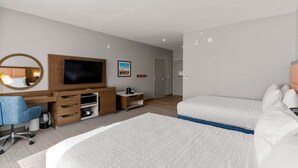 Ein modernes Hotelzimmer mit einem großen Bett, einem Schreibtisch mit Computer, einem Fernseher und einer kleinen Sitzecke.