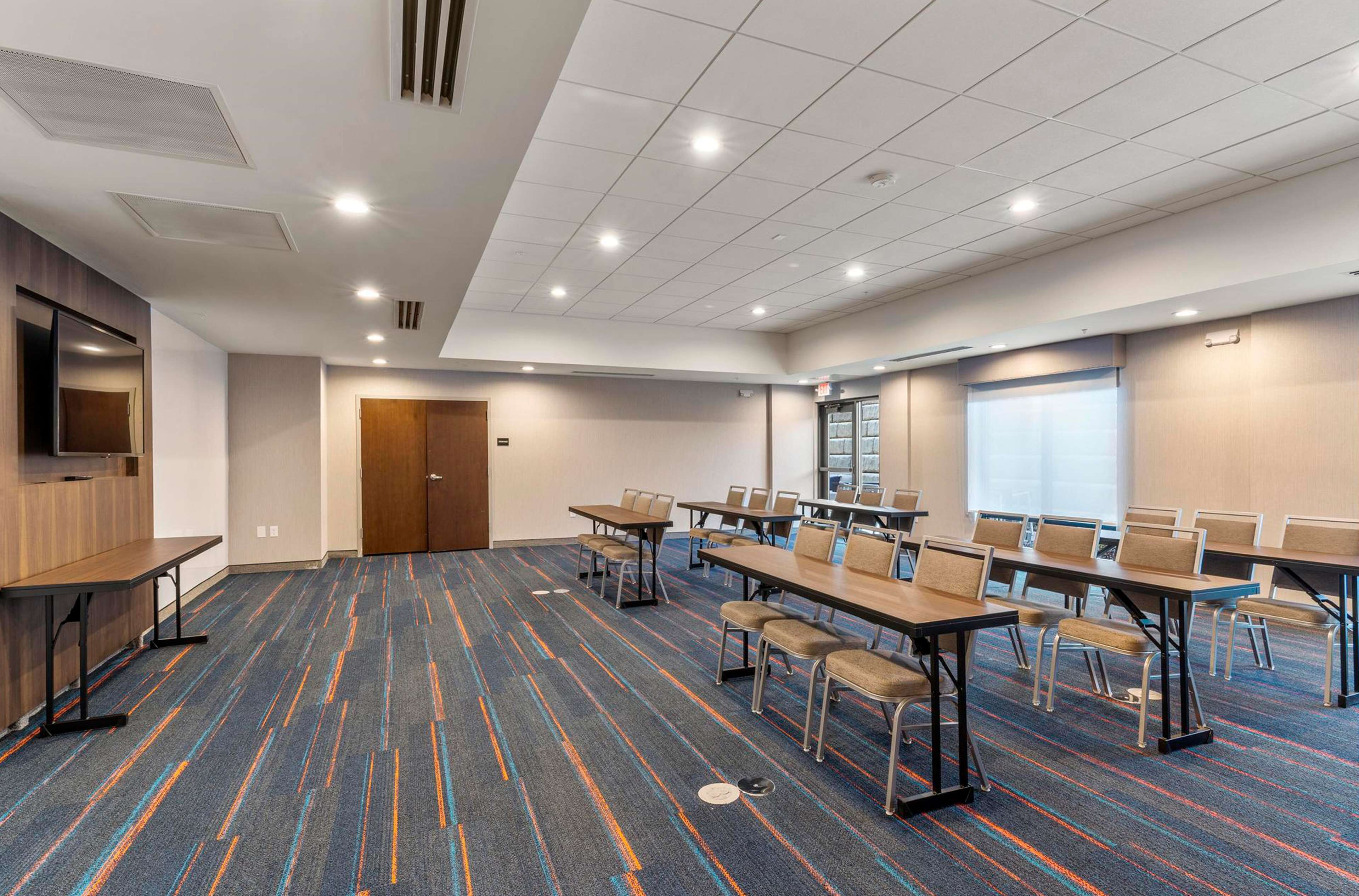 A conference room with tables and chairs, a television, and a door.