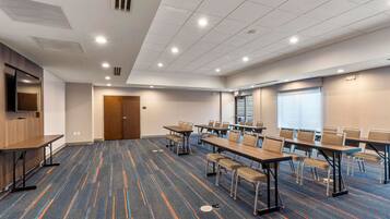 A conference room with tables and chairs, a television, and a door.