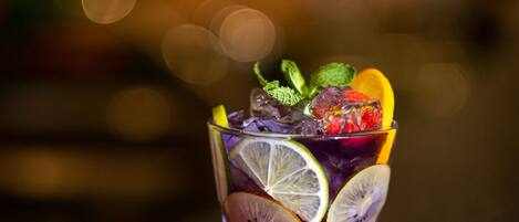 A glass filled with various fruits and mint leaves, placed on a textured surface.